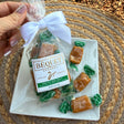 A package of Béquet Celtic sea salt caramels with a pretty bow, on a plate with individually wrapped caramels, on a woven mat