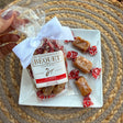 A package of classic Béquet caramels with a pretty bow, on a plate with individually wrapped caramels, on a woven mat