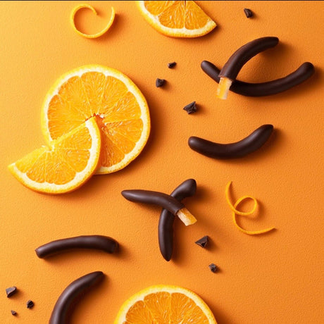slices of orange lay beside chocolate-dipped arcs of candied orange rind on an orange background